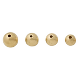 Four gold-colored hollow metal beads on a white background